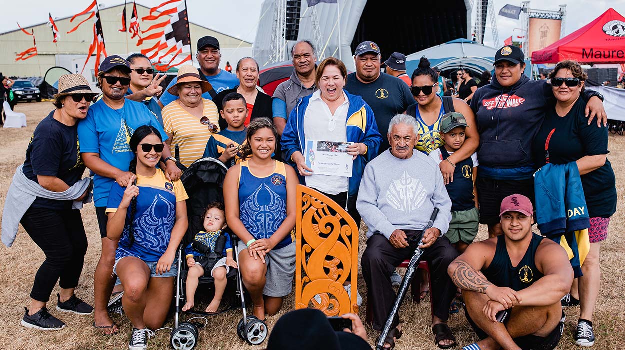A family taking a photo showing a trophy and a certificate.